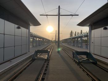 Railroad station platform against sky during sunset