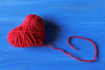 Close-up of heart shape wool ball on blue table