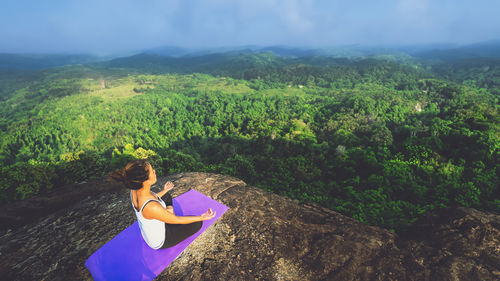 Rear view of woman sitting on mountain