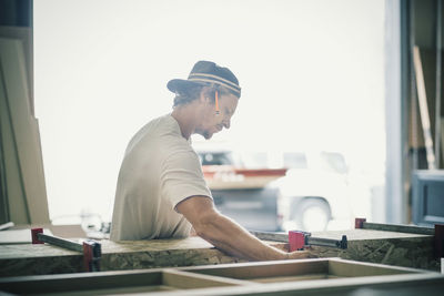 Side view of carpenter making furniture in factory