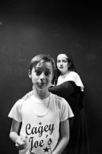 Portrait of boy standing by nun against black background