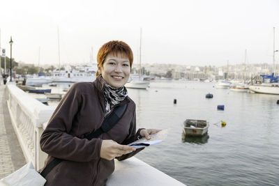 Woman with short red haircut reads malta map. curious woman stands near msida yacht marina. malta.