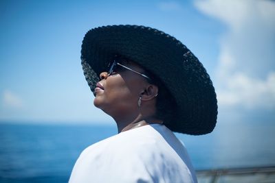 Side view of woman wearing hat against sea