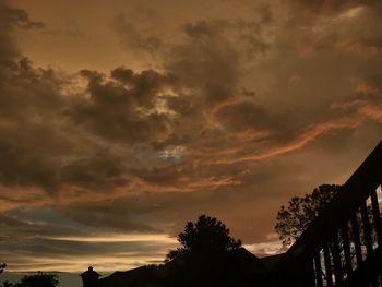 Low angle view of silhouette trees against dramatic sky