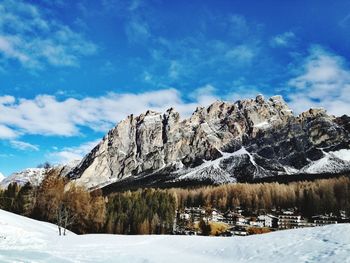 Low angle view of snowcapped mountains against blue sky