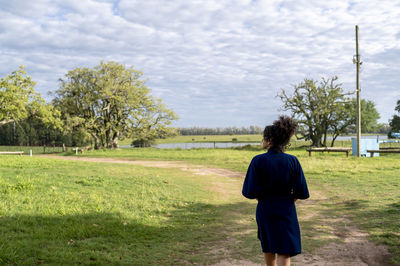 Rear view of man standing on grassy field against sky