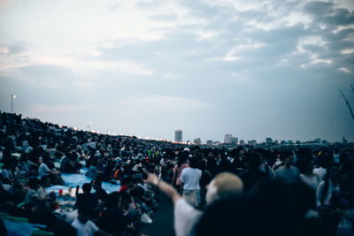 Crowd in city against sky