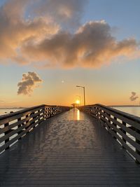 Pier over sea against sky during sunset