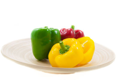 Close-up of bell peppers in plate against white background