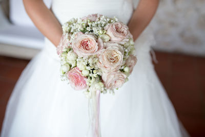 Midsection of bride holding flower bouquet