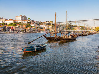 Sailboats moored in river against buildings in city