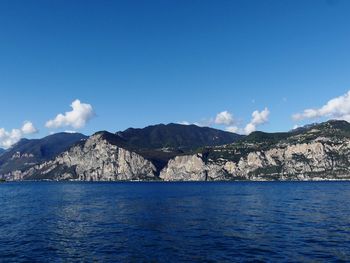 Scenic view of sea and mountains against blue sky