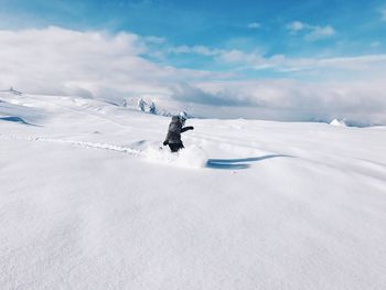 Person walking on snowcapped mountain against sky