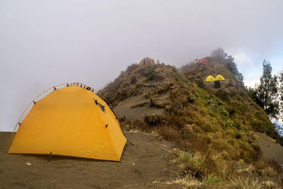 Yellow tent on mountain against sky