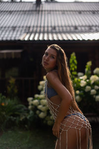 Young woman in bikini standing in the garden in the rain