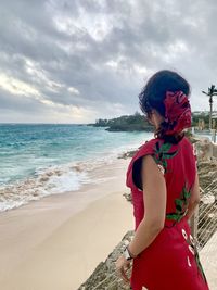 Woman standing at beach against sky