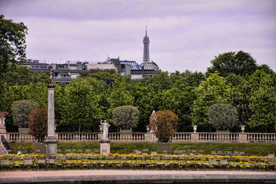 Empty chairs and statues on column in park with eiffel tower in distant