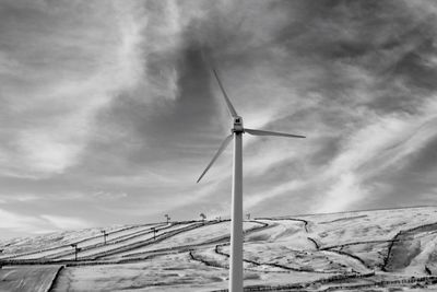 Low angle view of wind turbine against sky in black and white