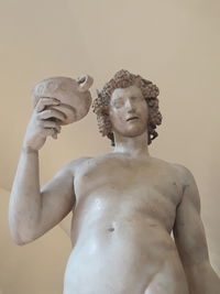 Statue of man with arms raised against gray background