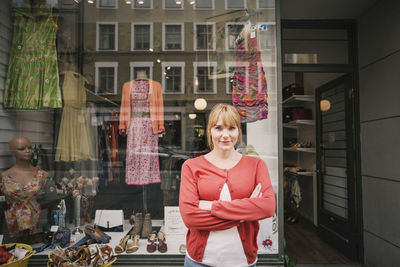 Smiling confident owner standing against thrift store