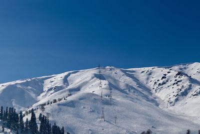 Scenic view of snowcapped mountains against clear blue sky