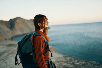 Rear view of woman standing by sea against sky