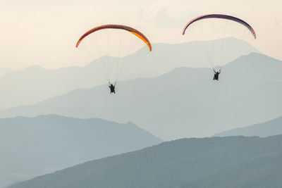 People paragliding against mountain range