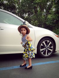 Portrait of girl standing against car on road