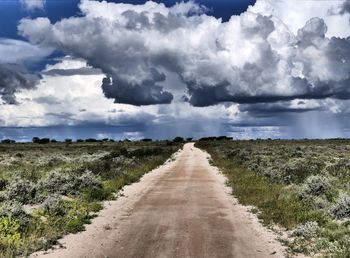 Dirt road along landscape and against sky