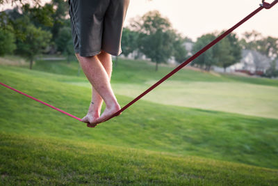 Low section of man slacklining at park 