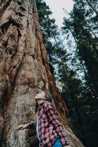 Low angle view of woman on tree trunk