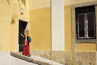 Side view of woman with backpack knocking door