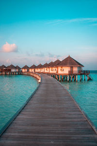 Pier over sea and houses against sky