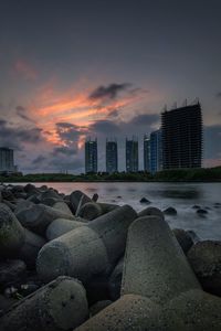 Scenic view of sea by buildings against sky during sunset