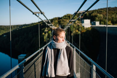 Woman on footbridge against sky