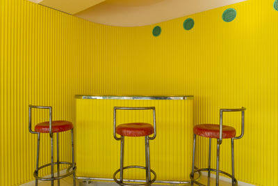 Empty chairs and table against yellow wall