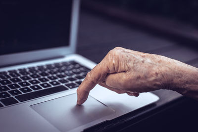 Old persons finger on laptop keyboard