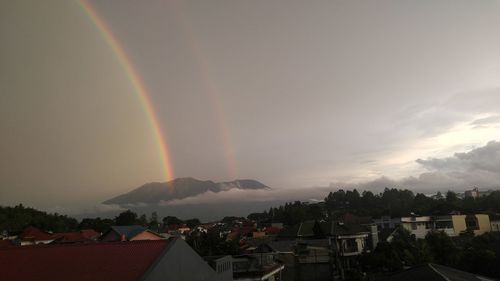 Rainbow over buildings in city against sky