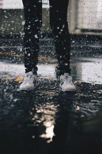 Low section of man standing on puddle