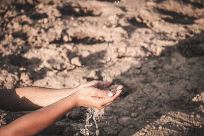 Cropped hand collecting water in hand outdoors