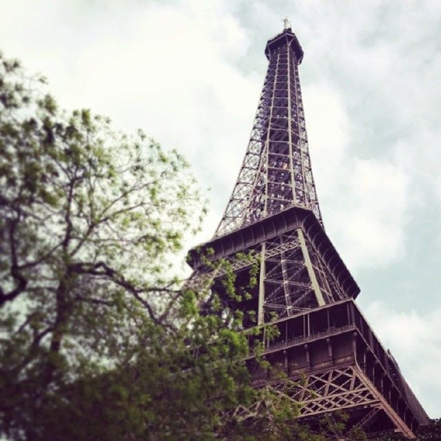 low angle view, architecture, built structure, tower, eiffel tower, sky, tall - high, tree, famous place, building exterior, culture, travel destinations, international landmark, history, metal, cloud - sky, tourism, architectural feature, capital cities, tall