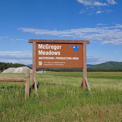 Information sign on field against sky