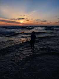Rear view of silhouette man on beach during sunset