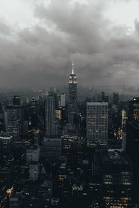 Illuminated modern buildings against cloudy sky in city