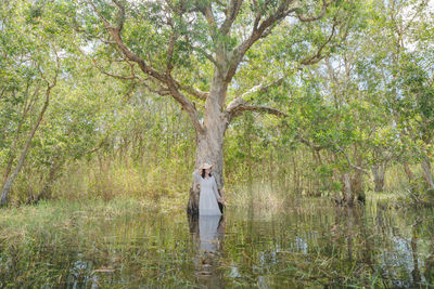 Woman standing by plants in forest