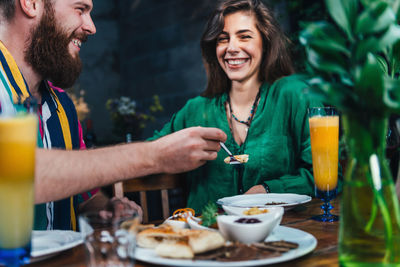 Smiling young man with drink on table at restaurant