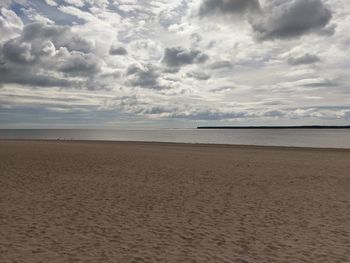 Scenic view of beach against cloudy sky