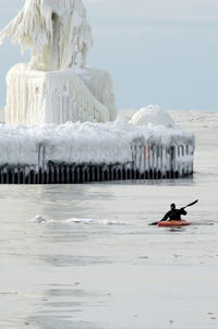 Extreme sport man in a kayak, near a frozen lighthouse