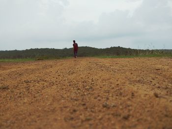 Full length of woman walking on field against sky