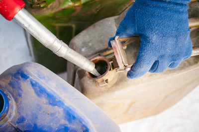 Cropped hand of man filling can with fuel during winter